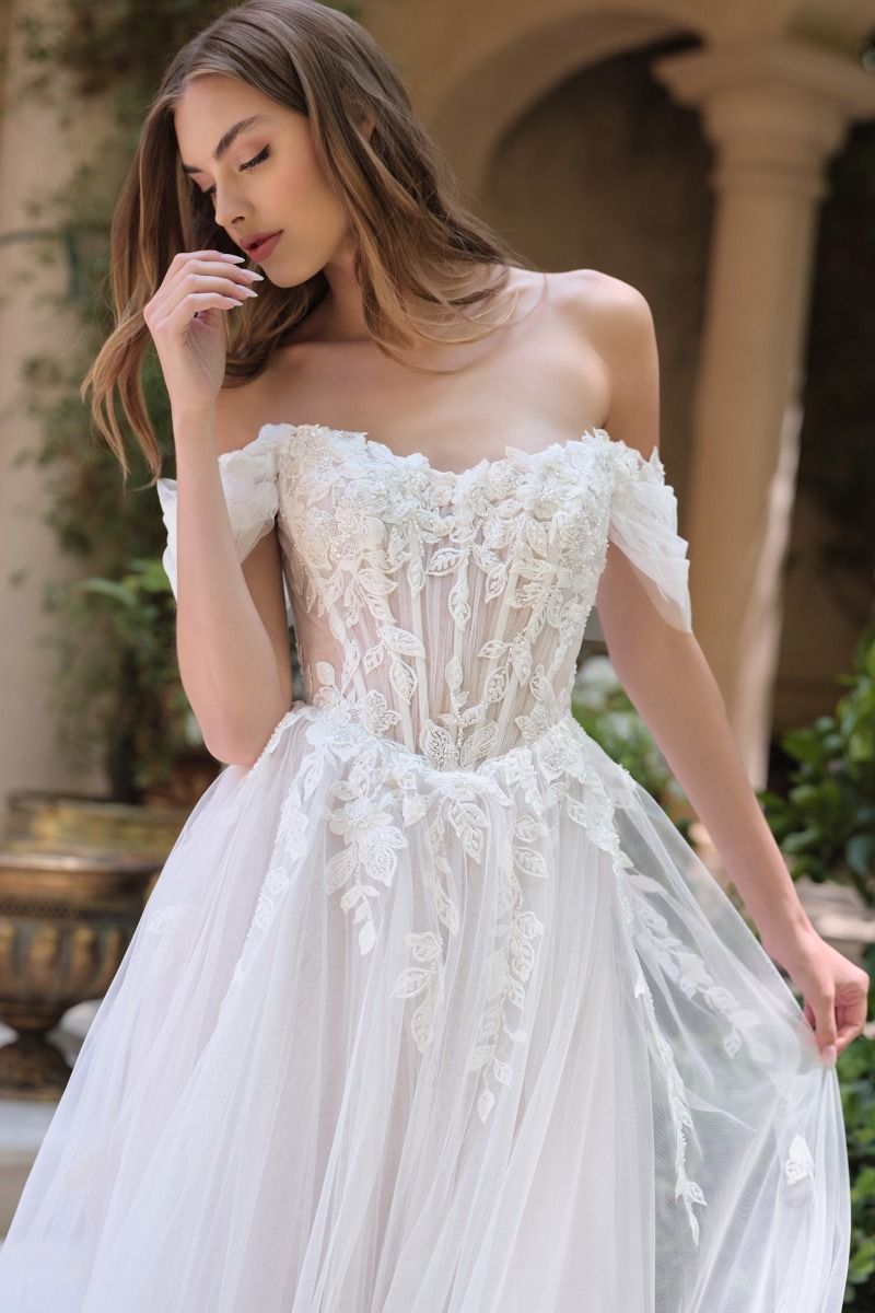 Vestido de Novia Escote ilusión con hombros descubiertos, apliques florales y mangas drapeadas transparentes.