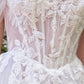 Vestido de Novia Escote ilusión con hombros descubiertos, apliques florales y mangas drapeadas transparentes.